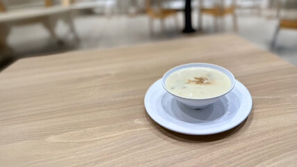 Mushroom soup served in a white bowl on a wooden table at a restaurant. Creamy mushroom soup in a white bowl sits on a wooden table at a restaurant.