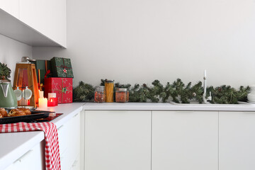 White kitchen counters with burning candles, gift boxes and Christmas decor
