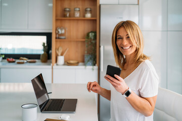 Woman Using Smart phone While Sitting at Kitchen Table