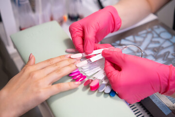 Nail master helps to select a nails color polish from the samples collection. A palette of...