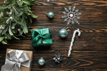 Christmas mistletoe branch with balls and gift boxes on wooden background