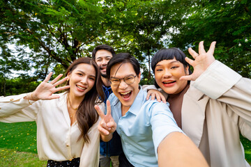 Group of Happy Asian millennial people friends enjoy and fun celebration reunion meeting using mobile phone taking picture together at dinner party in the garden at restaurant on holiday vacation.