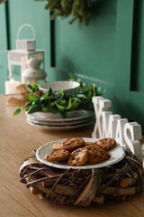 Wooden kitchen counter with Christmas decorations and cookies near green wall