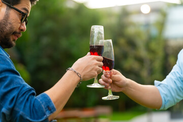 Group of Happy Asian millennial generation people friends enjoy and fun toasting red wine glasses celebration reunion meeting at outdoor dinner party in the garden at restaurant on holiday vacation.