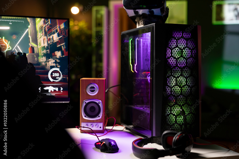 Poster neon lights illuminated components on gaming pc tower next to mouse, headphones, display and vr gogg