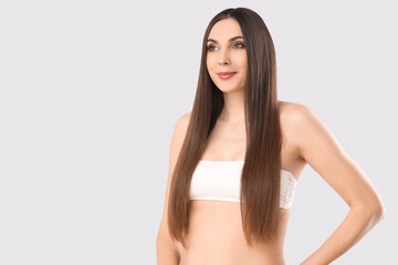 Young brunette woman with long hair on light background