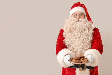 Santa Claus with plate of tasty cookies on white background