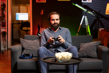 Portrait of man playing boring videogame on gaming console, feeling turned off by uninteresting...