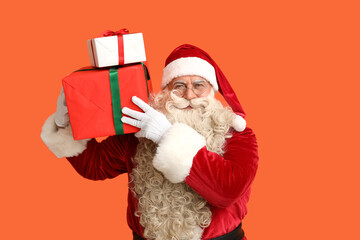Santa Claus with Christmas gifts on orange background