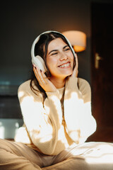 Young caucasian woman enjoying music on wireless headphones at home