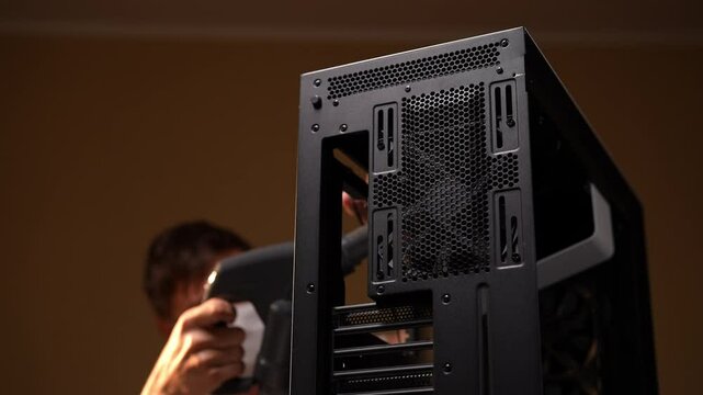 Professional technician male in face mask demonstrating professional computer maintenance by using compressed air to clean case and prevent overheating in workshop. Shooting in slow motion.