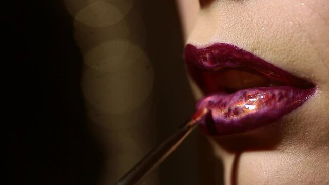 Makeup artist applying lipstick with brush, doing professional makeup. Woman with lipstick, makeup portrait. Red lips. Woman applying lipstick lip gloss. Makeup artist. Beauty lips with lipstick.