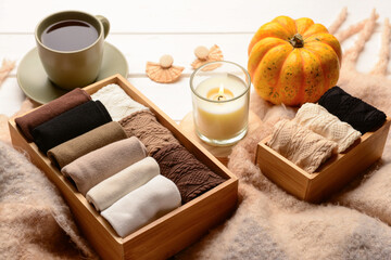 Basic color socks with candle, pumpkin, accessories and cup of tea on white wooden background