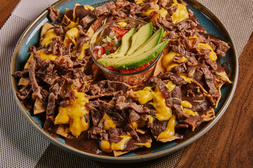 Plato de nachos con carne, queso amarillo, frijoles, y pico de gallo