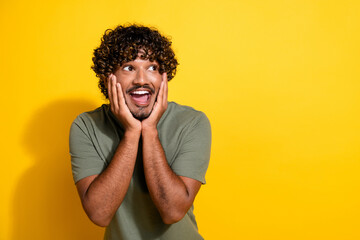 Photo of impressed ecstatic guy with curly hairstyle dressed khaki shirt look at offer empty space...