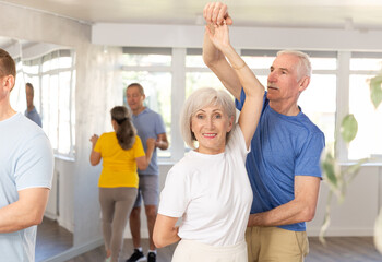Mature man in dance hall with female partner and dances Latin rumba. Hobby, healthy lifestyle...