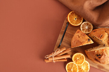 Wooden tray with tasty Panettone, slices of dried orange and cinnamon sticks on colorful background