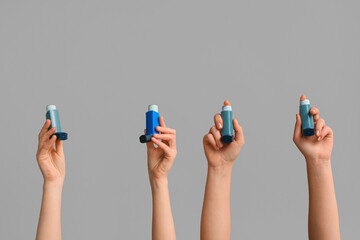 Female hands with modern asthma inhalers on grey background