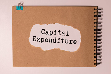 The text Capital Expenditures behind torn brown paper