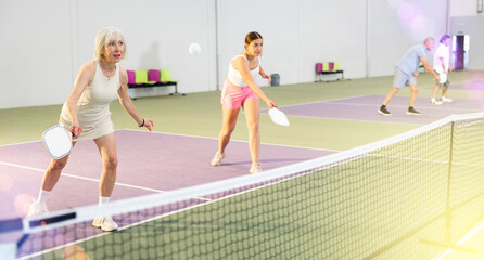 Obraz premium Athletic womens playing pickleball tennis on the pickleball court indoors