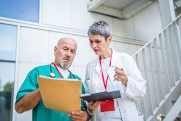 Two doctors check information from clipboard and document on staircase