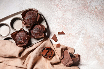 Baking mold with tasty chocolate muffins on white grunge background