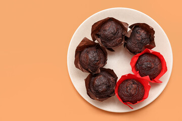 Plate with tasty chocolate muffins on beige background