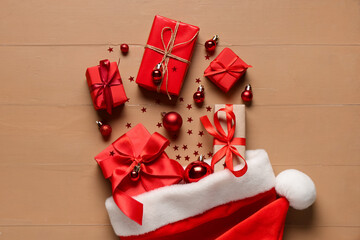Santa hat with Christmas gift boxes and balls on brown wooden background