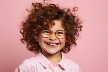 Portrait of a cute smiling little girl with curly hair and glasses on a pink background