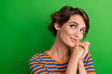 Photo portrait of pretty young girl look empty space hold hands together dressed stylish striped outfit isolated on green color background