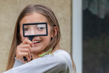 Girl Smiles While Looking at Insect with Magnifying Glass, California, USA, horizontal