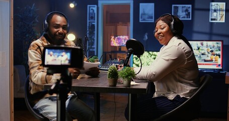 BIPOC influencers in studio using professional camera for internet show production on livestreaming platform. Content creators doing podcasting session with filming gear