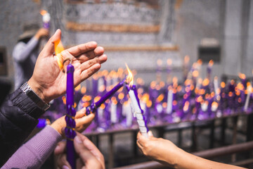 Hands of people with purple candle in front The lord of miracles faithful devotees of the religion....