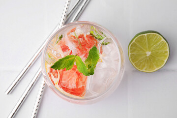 Refreshing water with grapefruit and mint in glass on white tiled table, flat lay