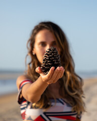 young woman holding a pine cone on beach