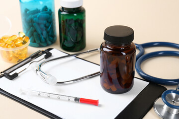 Pharmacist. Pills in plastic bottles, clipboard, syringe and stethoscope on beige background