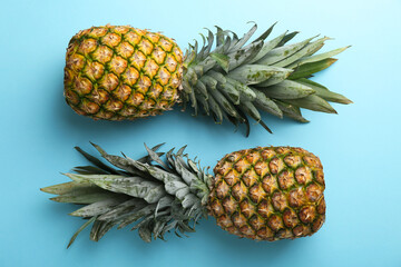 Fresh ripe pineapples on light blue background, top view