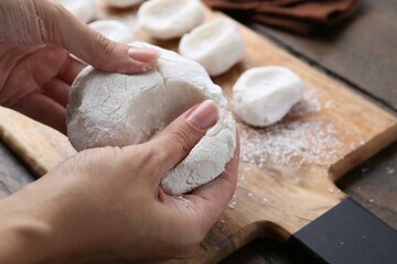 Woman making tasty mochi at wooden table, closeup
