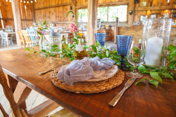 Wedding place setting on a wooden table in a barn with fancy glasses.