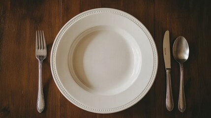 A dinner plate with a spoon and fork beside it, ready for a comforting bowl of homemade soup.