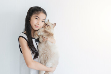 Obraz premium Girl and her furry friend: A young Asian girl with long dark hair holds her fluffy cat, both looking content against a white background.