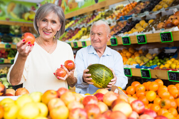 Fototapeta premium Portrait of Married couple buying apples and watermelon at grocery shop