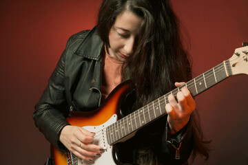 Female guitarist playing electric guitar with focus.