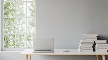 A modern workspace featuring a laptop on a clean desk beside a stack of books and a bright window with greenery outside.