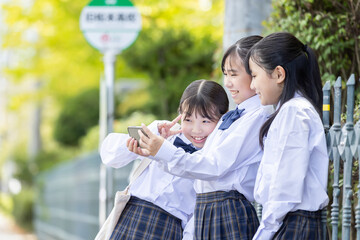 バス停でスマホをみる学生