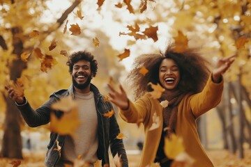 Afro couple joyfully playing in a park during autumn, throwing colorful leaves and enjoying a fun day outdoors