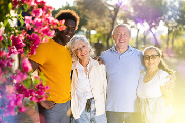 Naklejka premium Happy multiethnic people standing together, hugging and looking at the camera in the sunny weather, afternoon in autumn park