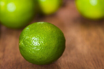 Fresh Whole Key Lime on Wood (Very Shallow Depth of Field, Focus on the front of the lime)