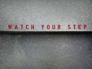 Cement steps stair with caution sign written WATCH YOUR STEP , to warn people to be careful when...