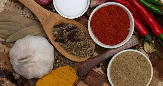 Asian favour spice green red dry chilli powder onion garlic ginger cinnamon cardamon turmeric fennel seeds bay leaf clove star anise wooden spoon blows on palm leaf plate over black slate background